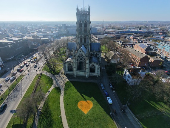 Picture of Doncaster Minster on a sunny clear day with a yellow heart painted on the grass infront