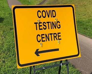 a yellow sign saying covid testing 