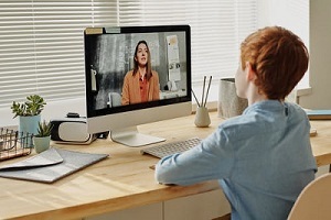 child sat at a desk having an online teaching lesson 