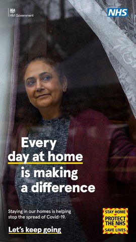 woman peering out of window staying safe at home