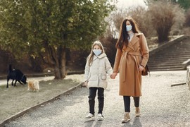 woman holding daughters hand wearing face coverings