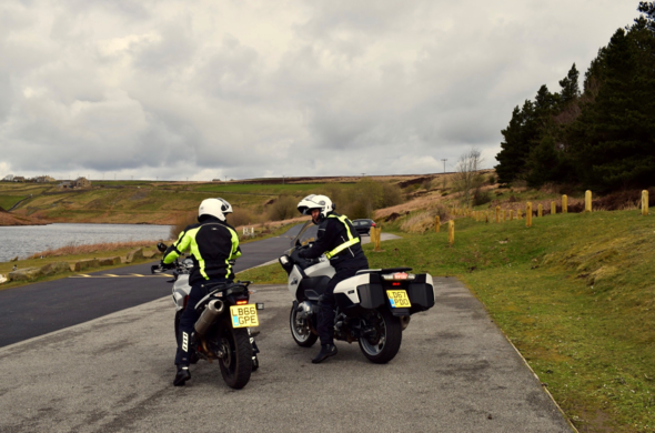 Two people on motorbikes in a layby.