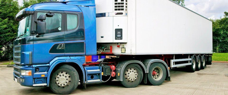 A blue and white lorry being driven in a parking lot