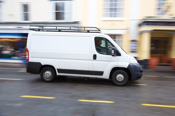 White van driving down street