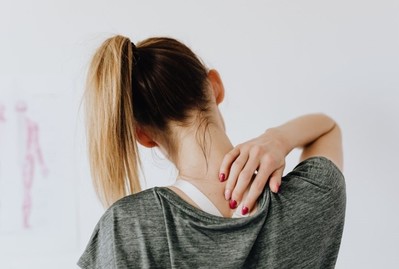 woman rubbing sore shoulder