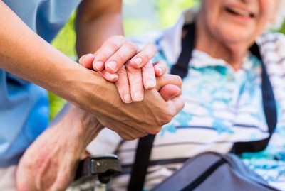 carer helping an elderly woman and holding her hand