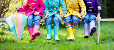 Kids sitting on a bench wearing different coloured wellies 