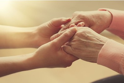 young woman's hands holding elderly woman's hands