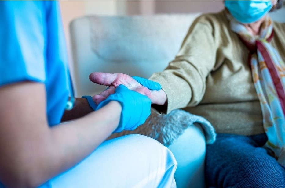 female carer attending to an elderly woman in a care home