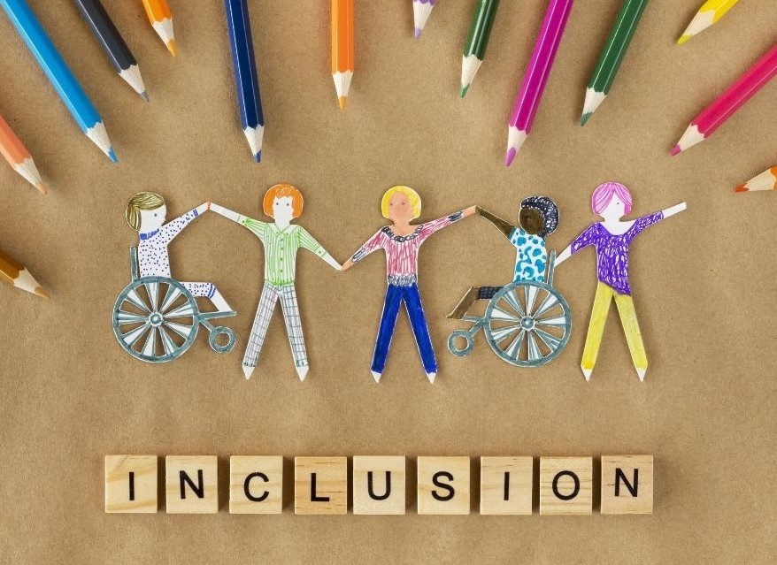 image of paper cut out children, two in wheelchairs, with the word: 'Inclusion' below