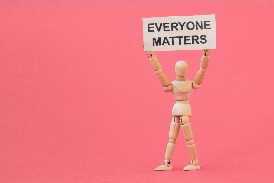 wooden artist's model holding up a sign that reads: 'Everyone matters'.