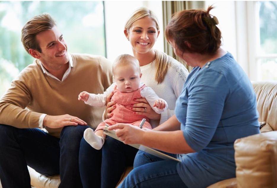 Health visitor sitting with parents and their baby