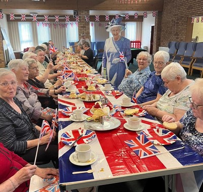 Older ladies enjoying afternoon tea in New Cumnock, with union flags and decorations