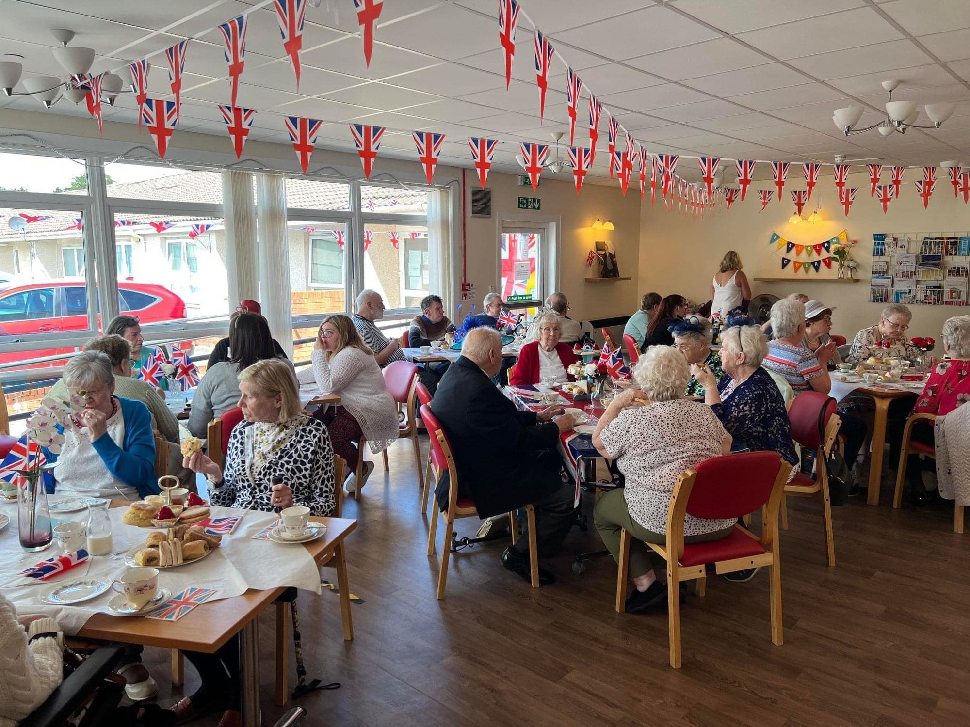 Tea party attendees enjoying tea, cake and sandwiches