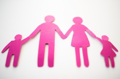 pink paper cut-out family against a white background