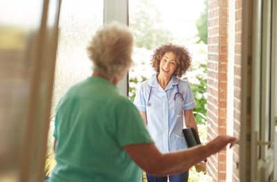 elderly woman opening her door to a female care worker