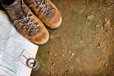 Hiking boots beside a map on a muddy ground