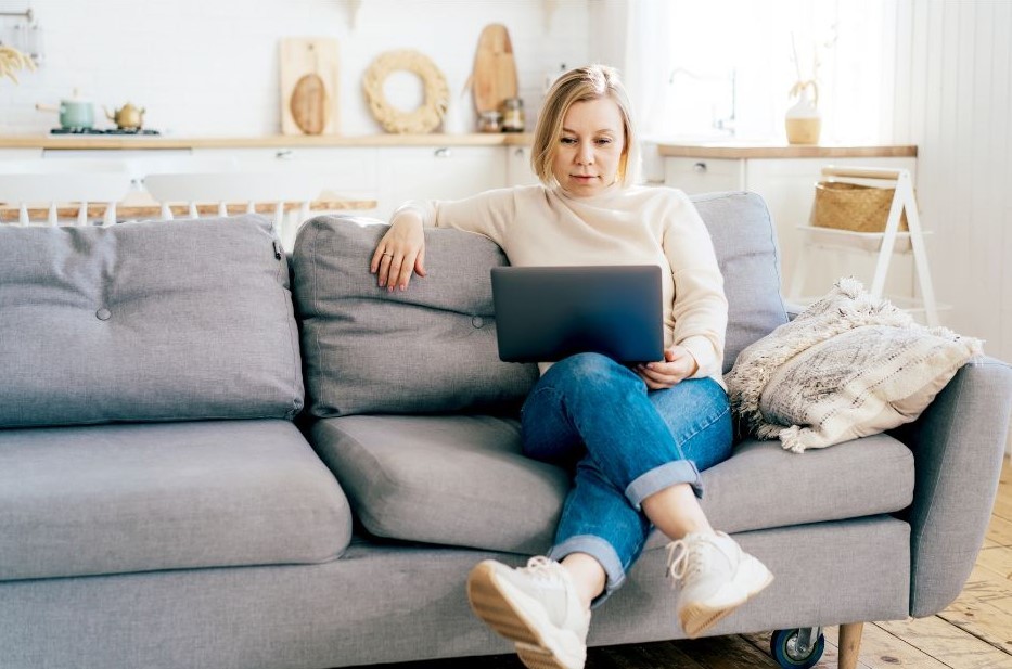 woman sitting on a sofa while using her laptop