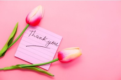 Two pink tulips beside a thank you note