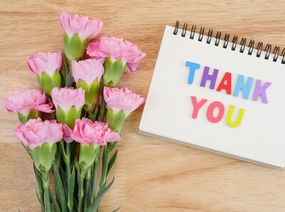 A thank you note beside a bouquet of pink flowers