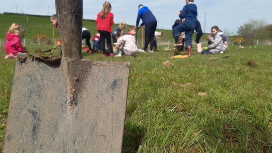 Shovel in ground, people are out of focus in background