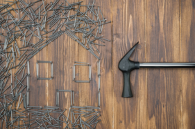 Hammer with nails arranged in the shape of a house