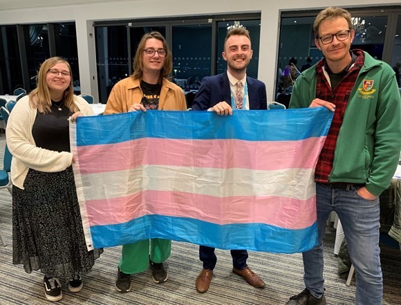 Councillor Jake Bonetta (second to right) proposed the motion which was seconded by Councillor Joe Whibley (far right) stand with the trans flag