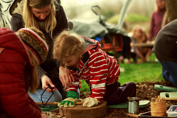 Children taking part in activity, with adult helping to saw wood. Credit: Tetiana Kravets 