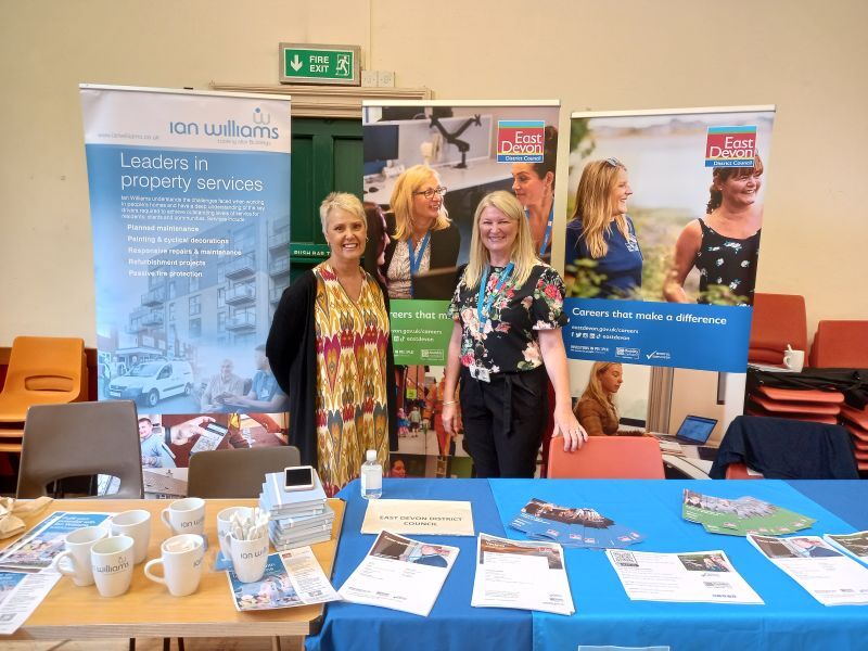 Photo of representatives from East Devon District Council and Ian Williams stood at stalls at the Honiton job fair