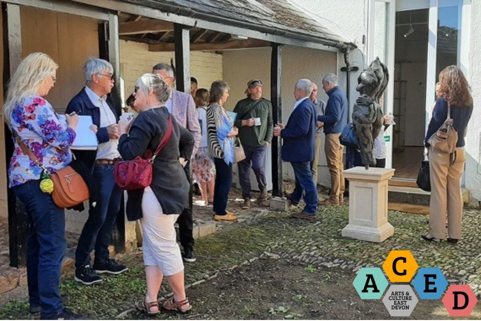 Photo of a group of people have conversations. ACED logo in bottom right corner
