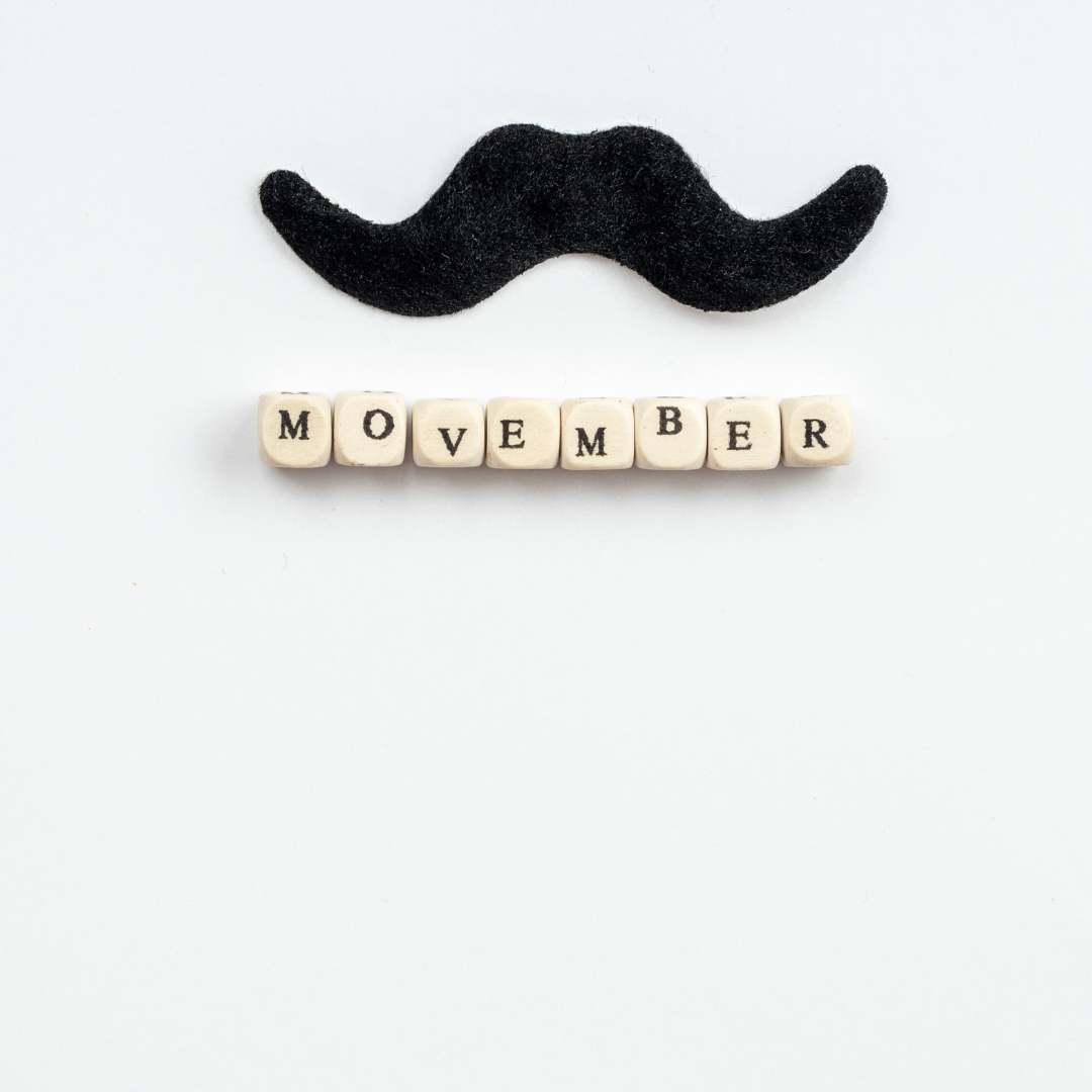 A felt moustache and scrabble tiles that spell Movember on a white back ground 