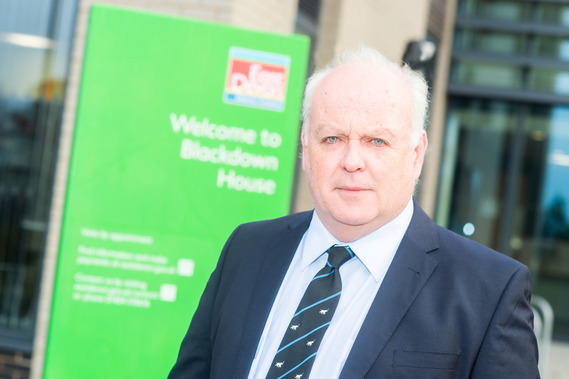 Photo of Councillor Arnott stood in front of the entrance of Blackdown House