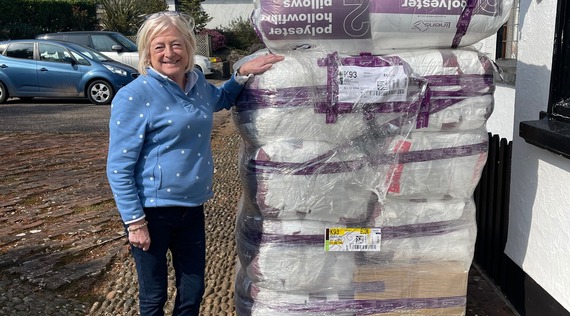Photo of a member of the Dream-A-Way team next to a pile of bedding