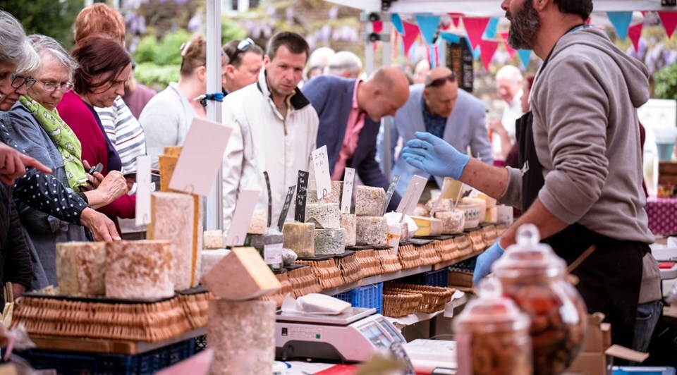 Photo of a stallholder surrounded by food and event attendees