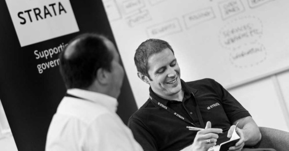 Two Strata employees sat down, one writing in a notebook