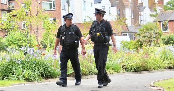 Two police officers walking through a park