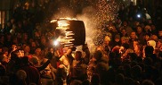 A person holds a tar barrel in the middle of a crowd of people