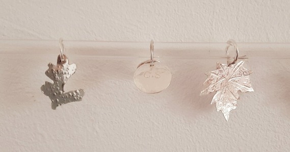 Silver Pendant decorations in the shape of leaves and a circle hanging from hoops 