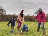 2 adults and 2 children planting a tree