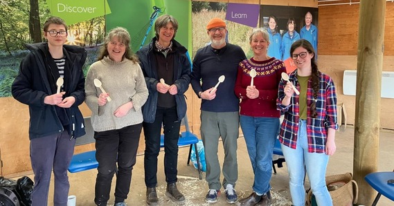 Group of people holding carved wooden spoons at Seaton Wetlands' Discovery Hut