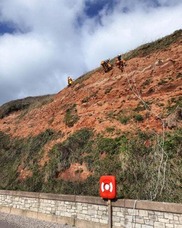 A cliff with people on ropes carrying out an inspection