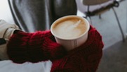 Gloved hands holding a coffee cup
