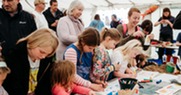 Group of people of a range of ages in a marquee at Sea Fest taking part in craft activities 