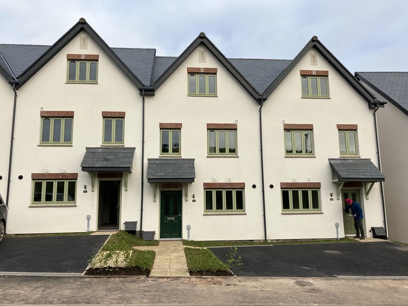 Exterior of three three-storey houses painted white with black roofs