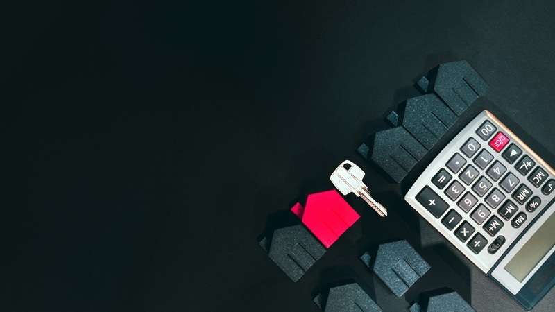 A calculator with a silver key and black and red house icons on a black background