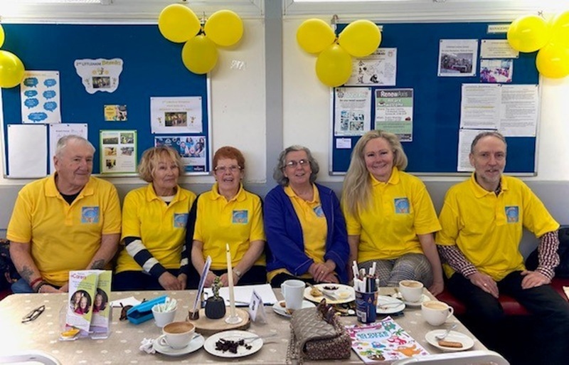 Six residents sat in a group all wearing yellow t shirts