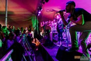 Musicians performing on stage to the audience in a tent