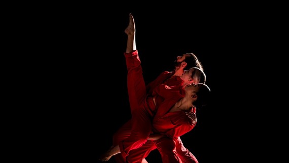 Four dancers in a line at an angle with legs straight up in the air