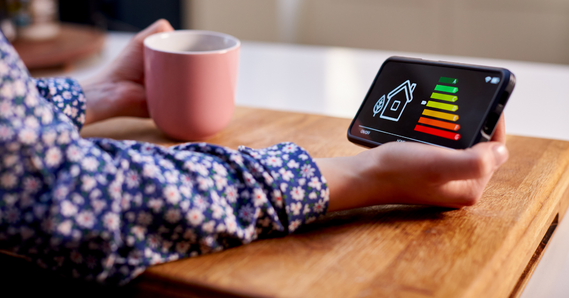 Close up of woman holding smart energy meter in kitchen measuring energy efficiency