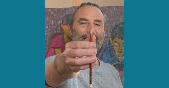 Alex Cree holding a pencil, with a painting in the background